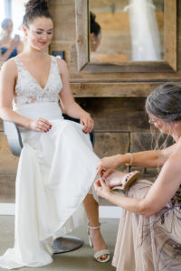 mother of bride helping her put on her kelly and katie heels