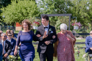 groom walking down the aisle with mom and grandmother