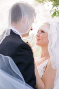 bride under veil with her husband